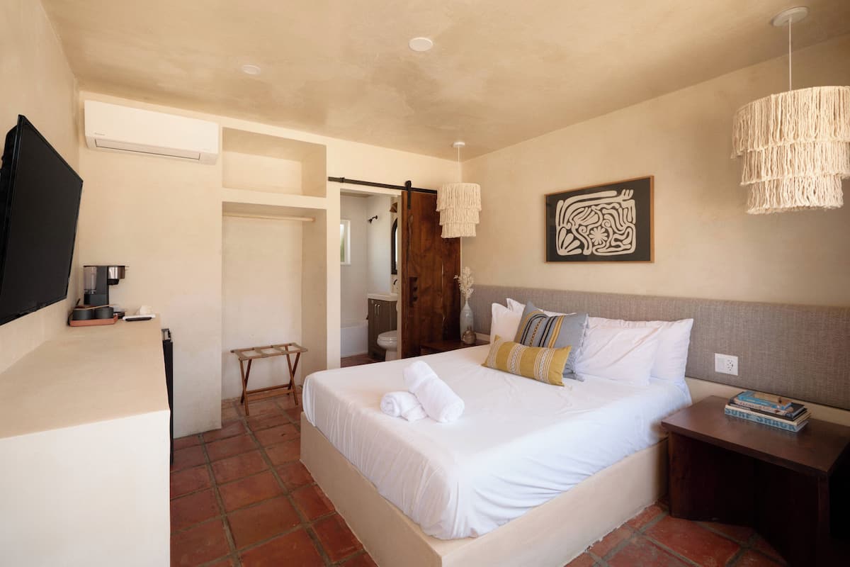 A hotel room with a bed, bedside table, and a TV mounted on the wall.