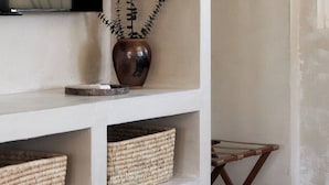 A room with a television mounted on the wall, a potted plant, and woven baskets on shelves. - Los Bungalows (Imperial Beach)