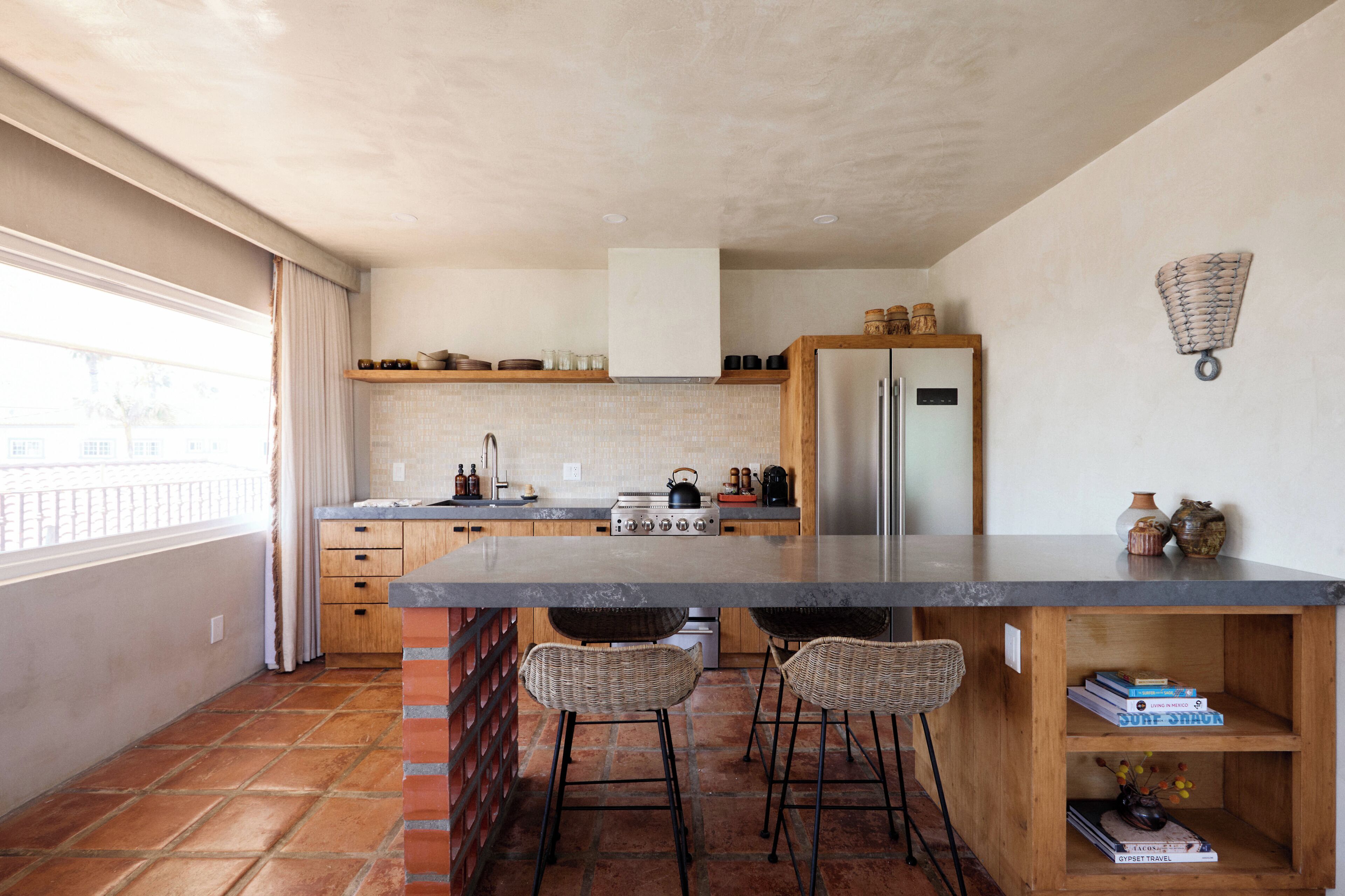 A modern kitchen with a large island, wooden cabinets, and a brick accent wall.