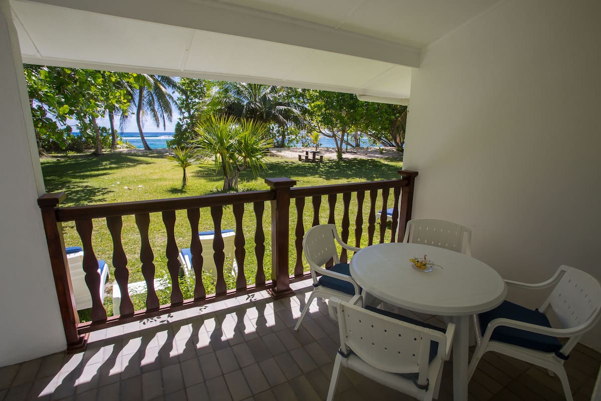 Un balcon avec vue sur l’océan, une petite table et deux chaises.