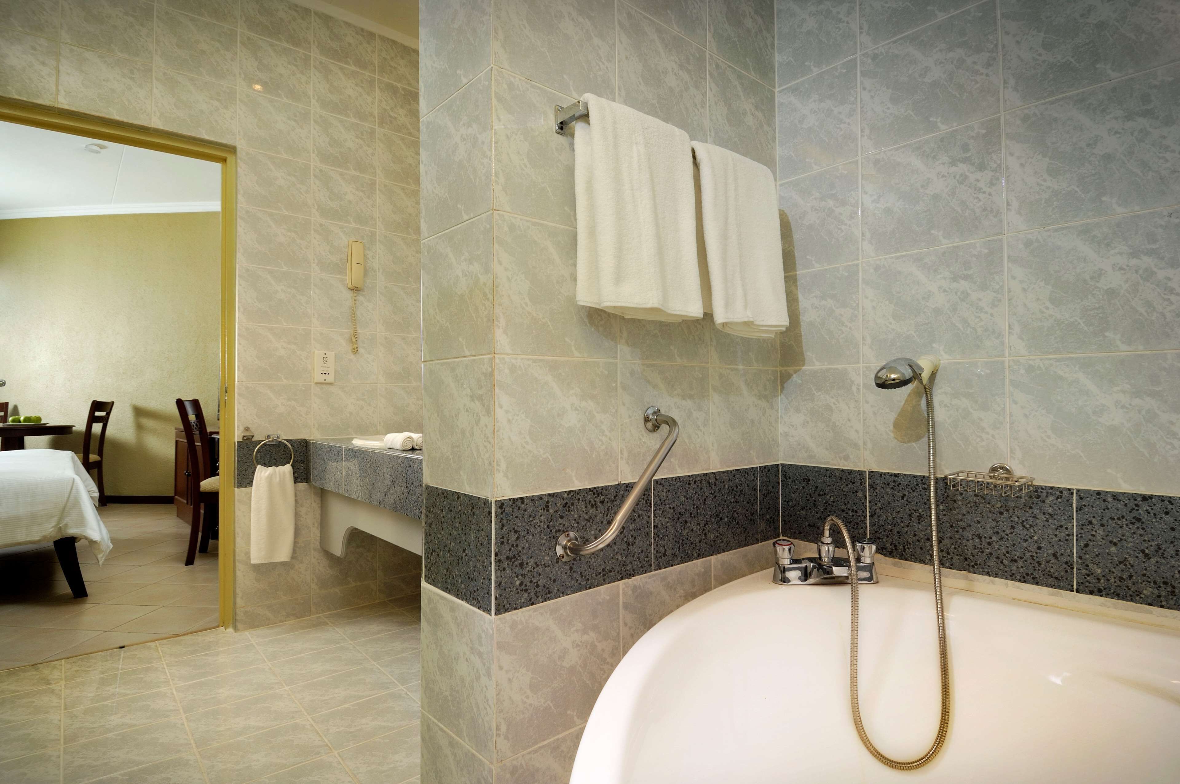A bathroom with a bathtub, a shower, and a vanity with a towel rack.