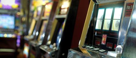 A row of slot machines with illuminated screens and buttons.