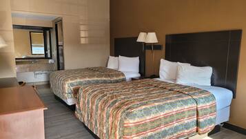 A hotel room with two beds, a bathroom, and a desk.
