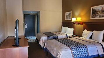 Une chambre d’hôtel avec deux lits, un bureau avec une télévision et une lampe.