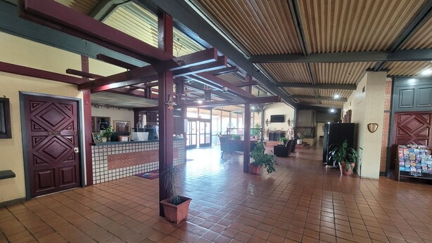 A spacious lobby with a tiled floor, a reception desk, and several potted plants.