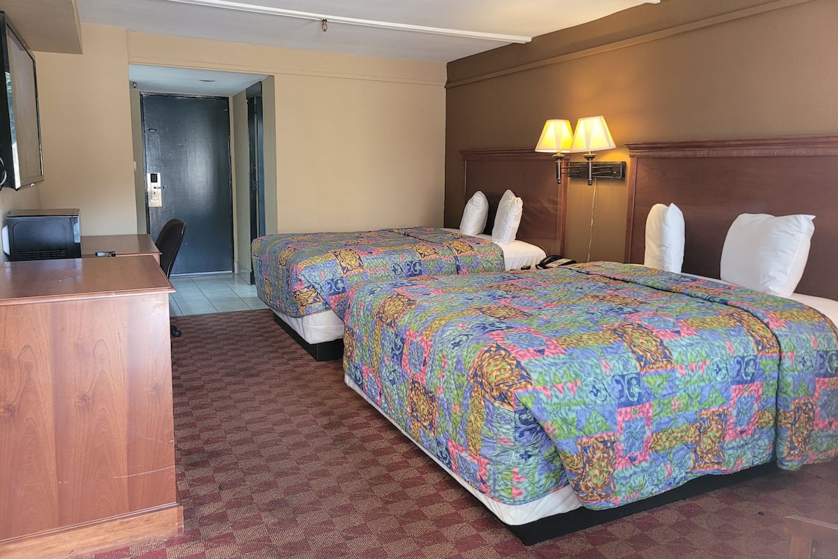 Une chambre d’hôtel avec deux lits, un bureau et une chaise.
