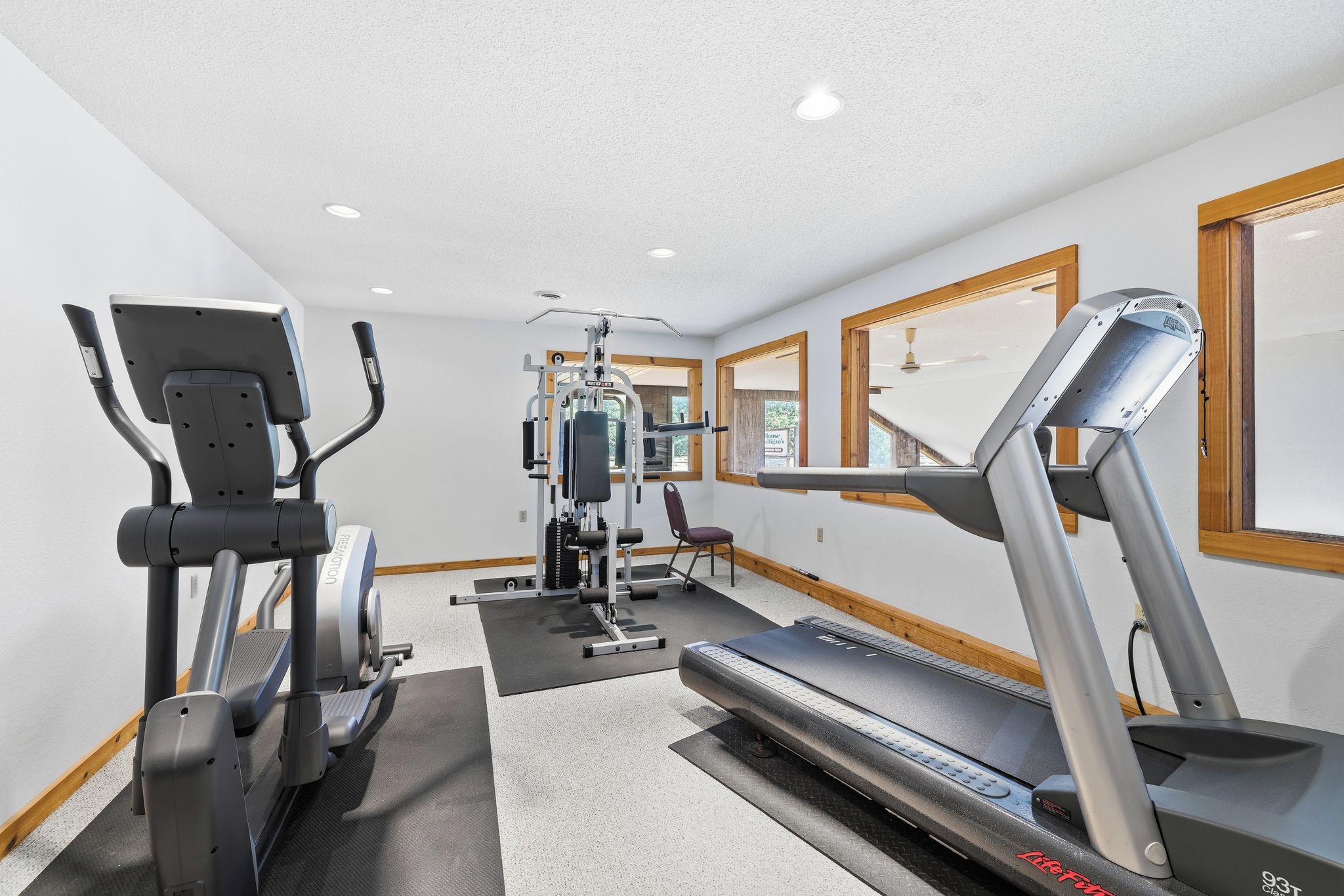 Un gimnasio con equipo de cardio, máquinas de pesas y un espejo grande.