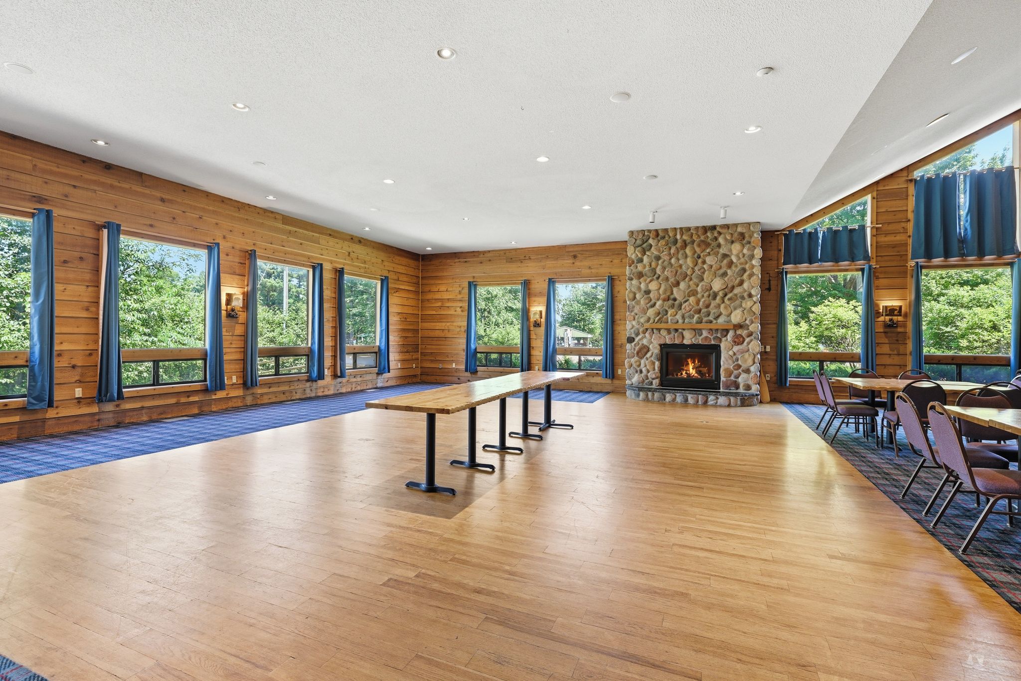 Una habitación amplia con una larga mesa de madera, varias ventanas y una chimenea de piedra.