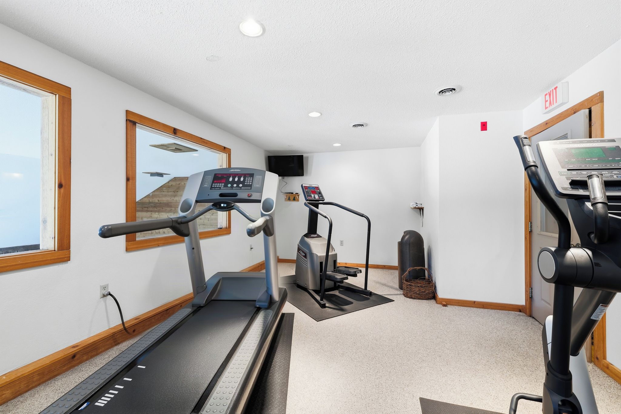 A gym with treadmills, a stationary bike, and a wall-mounted TV.