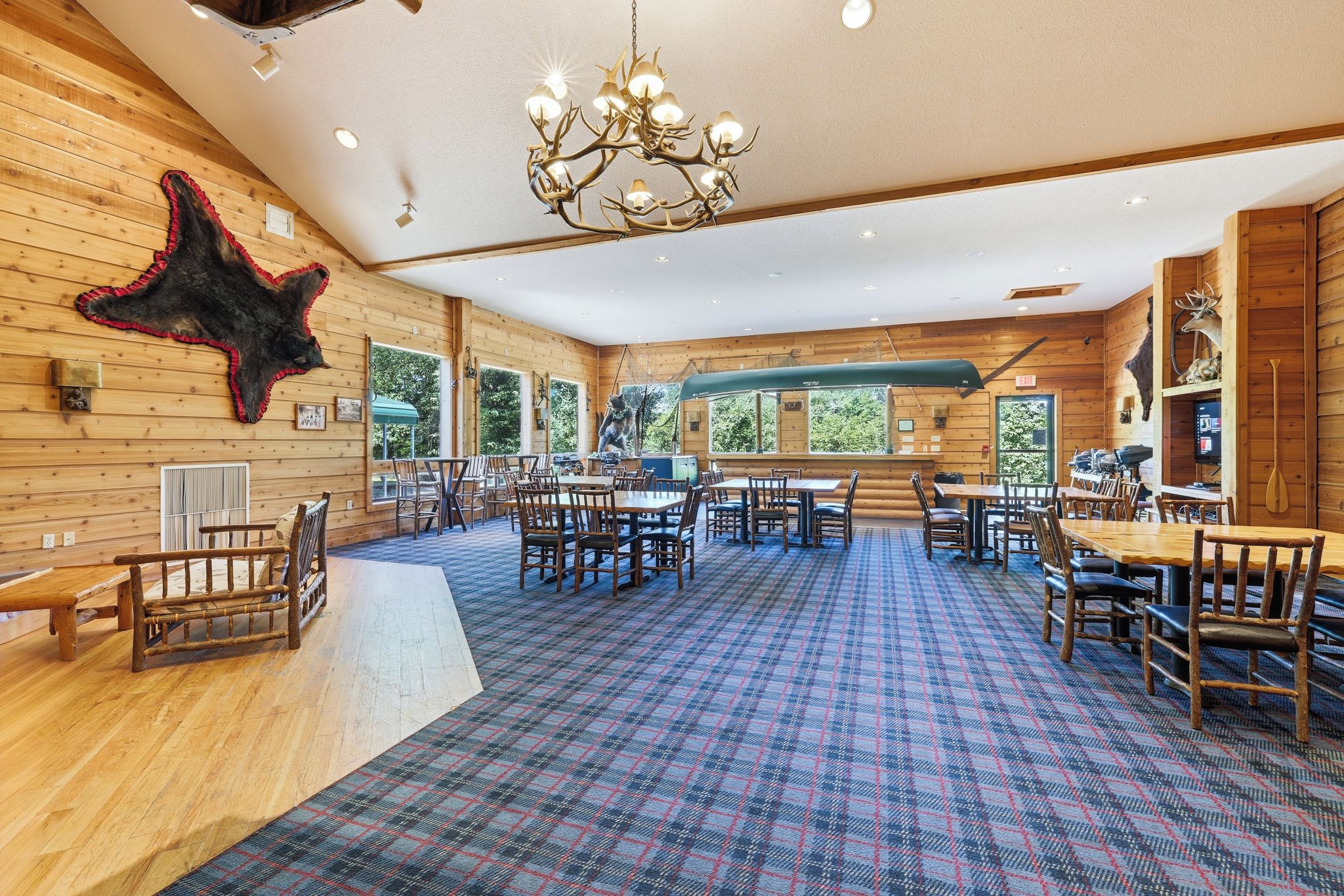A spacious room with a plaid carpet, wooden walls, and a chandelier.