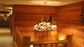 A wooden interior with a staircase, a chandelier, and a wooden railing.