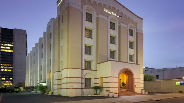 A large, multi-story building with a prominent arched entrance and a sign reading "Holiday Inn Express."
