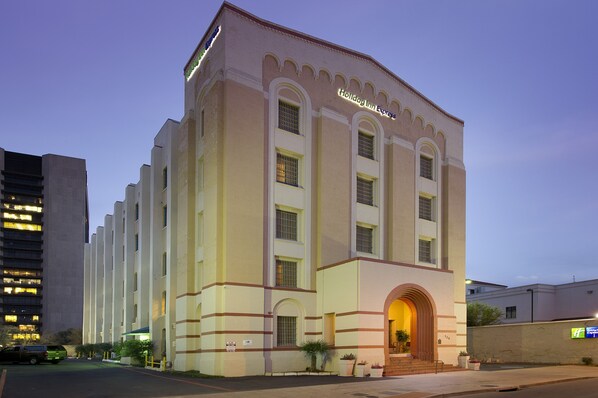 Um edifício grande, com vários andares e uma entrada em arco destacada, com uma placa que diz 'Holiday Inn Express'.