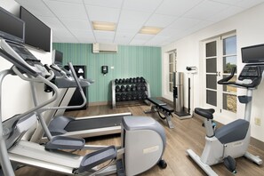 Un centre de remise en forme équipé de tapis de course, d’un vélo d’appartement et d’un banc de musculation.