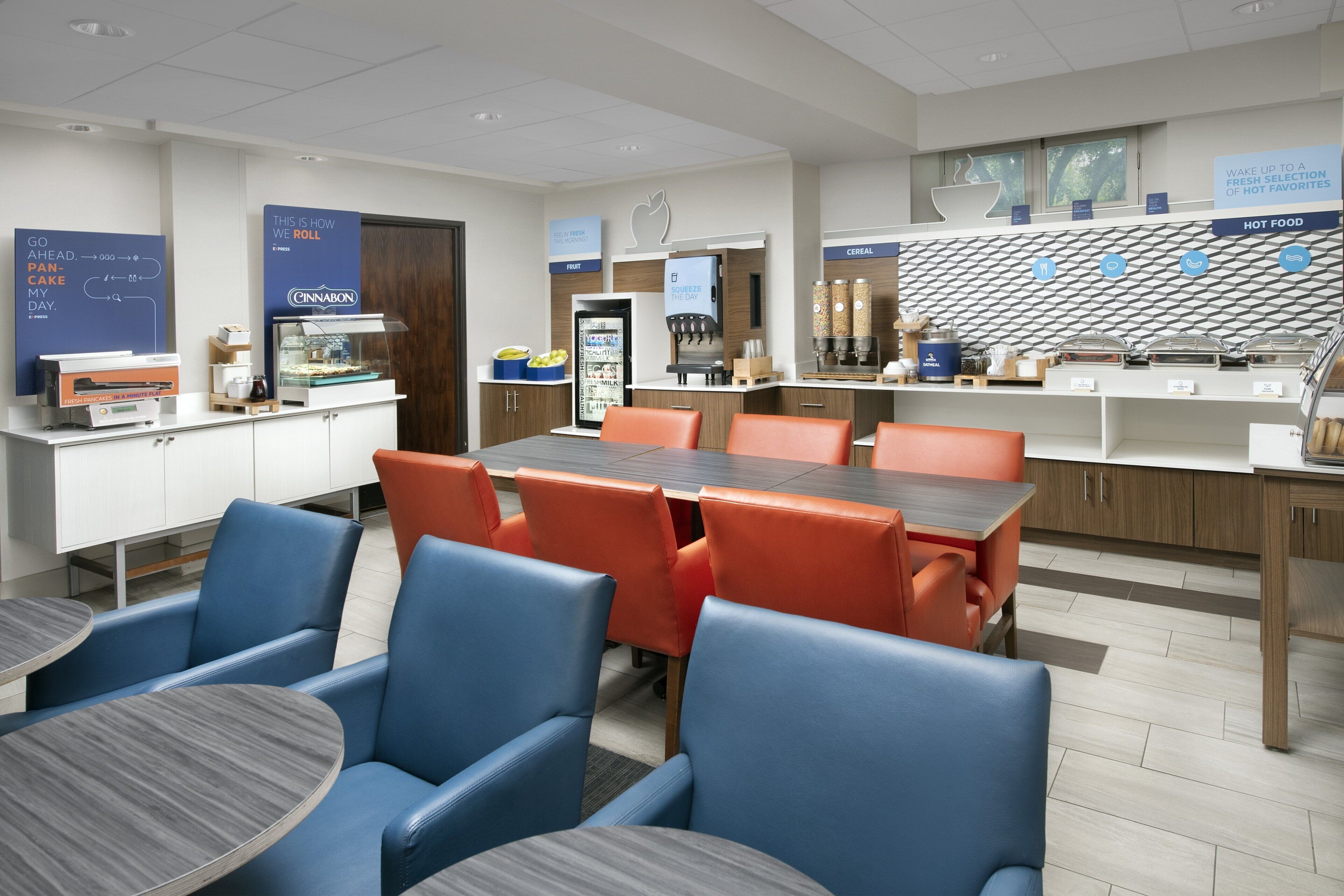 A modern breakfast area with seating, a display case, and a refrigerator.
