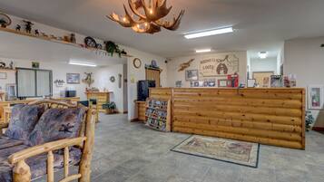 A lodge interior with a wooden reception desk, a large antler chandelier, and a rustic decor theme.