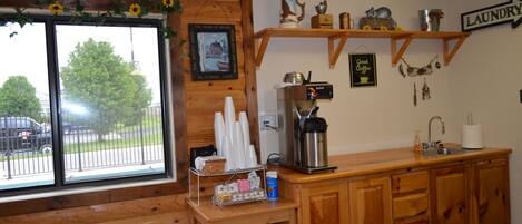 A kitchen with wooden cabinets, a coffee maker, and a window with a view of a street and trees.