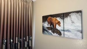 A room with a beige wall, a window with beige curtains, and a framed wildlife painting of a bear on a rock. - Booneslick Lodge of Neosho (Neosho)