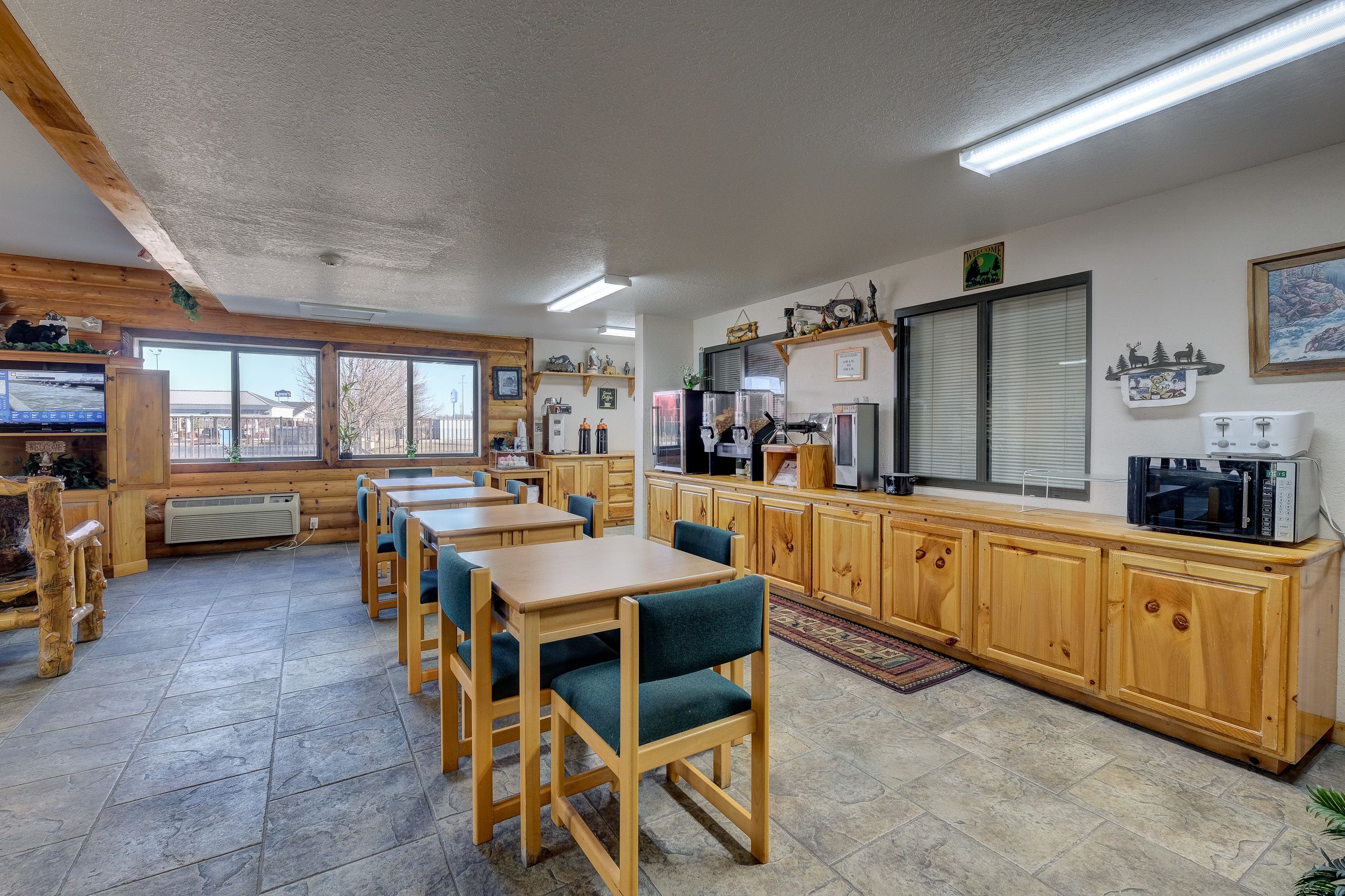 Eine Kücheneinrichtung im Chalet-Stil mit Holzschränken, einem Essbereich mit Tischen und Stühlen sowie einem großen Fenster mit Blick auf die Umgebung.