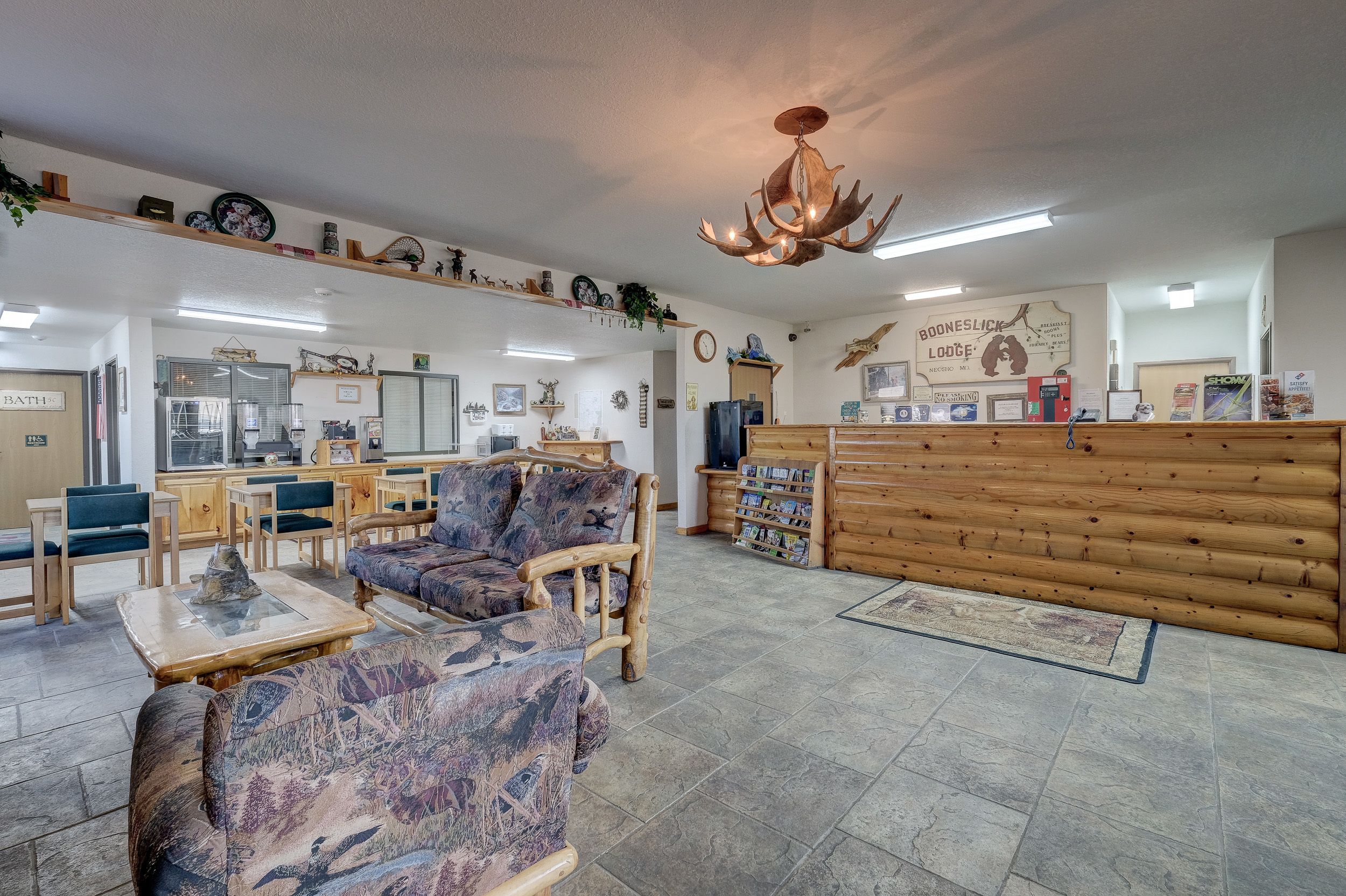 A spacious lobby with wooden furniture, a reception desk, and various wall decorations.