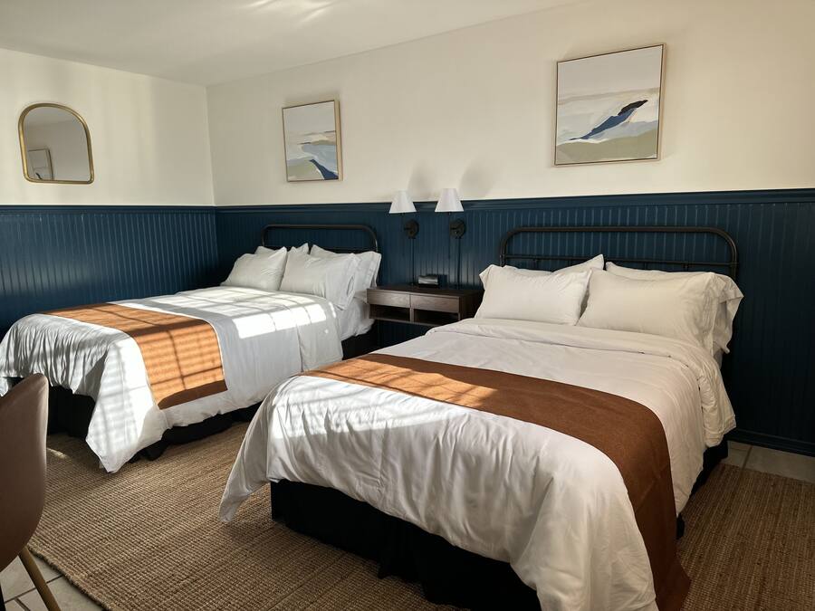 Een hotelkamer met twee bedden, een nachtkastje, een stoel en kunst aan de muren.