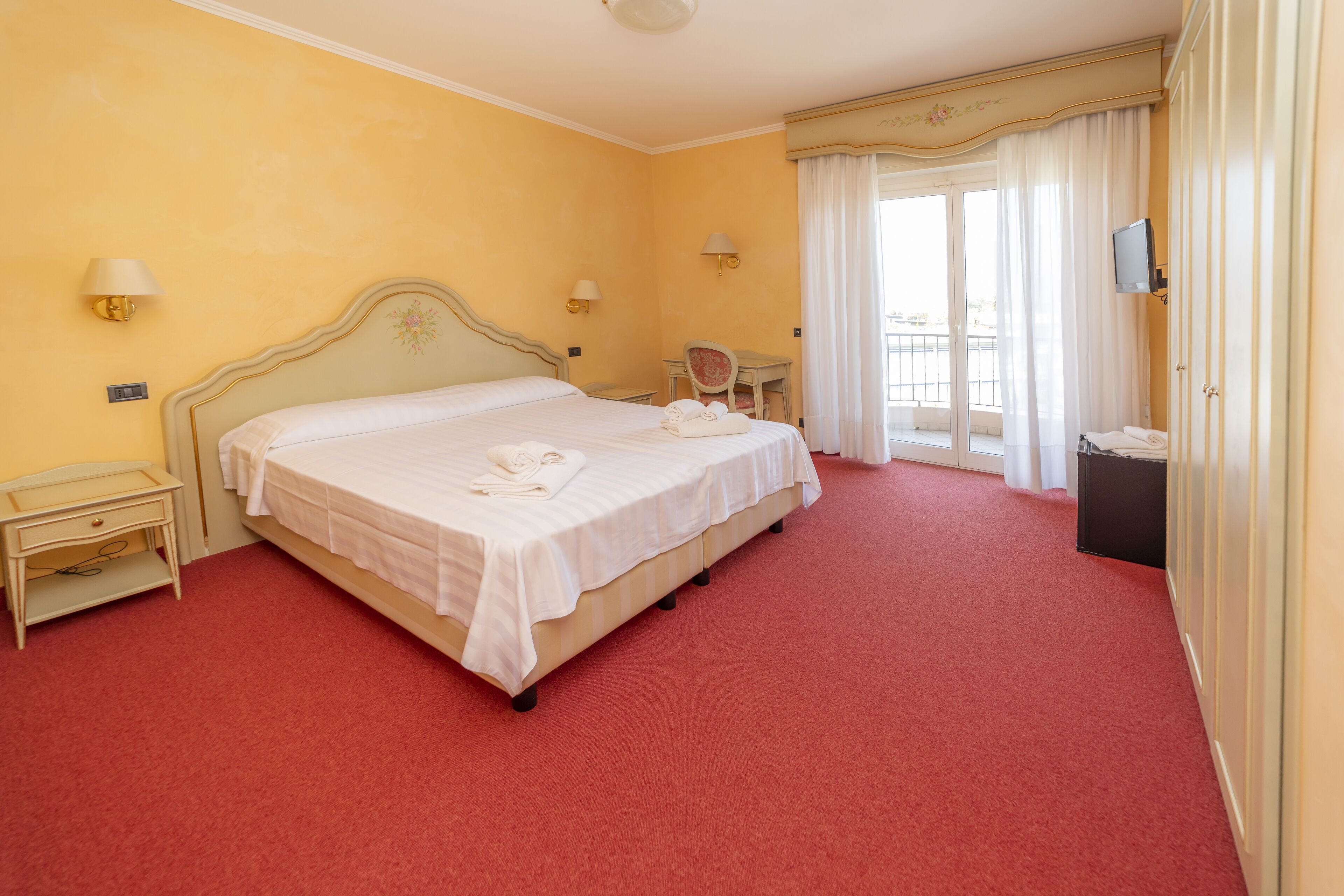 Ein Hotelzimmer mit einem Einzelbett, einem Schreibtisch, einem Stuhl und einem Fernseher.