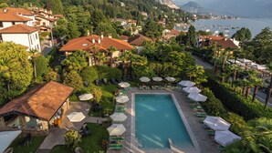 A resort with a swimming pool, lounge chairs, and umbrellas. - Hotel Della Torre (Stresa)