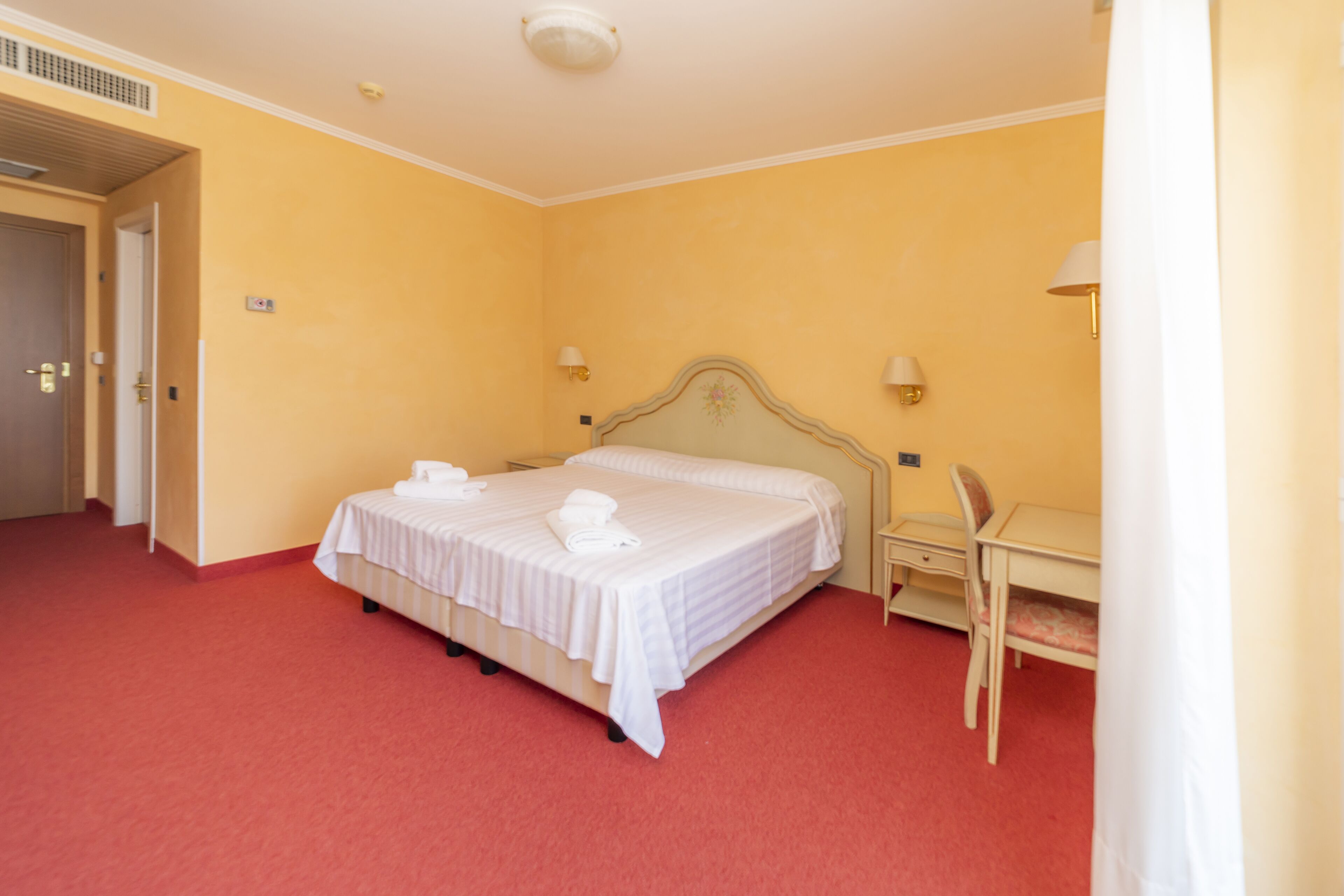 A hotel room with a double bed, a desk, and a chair.