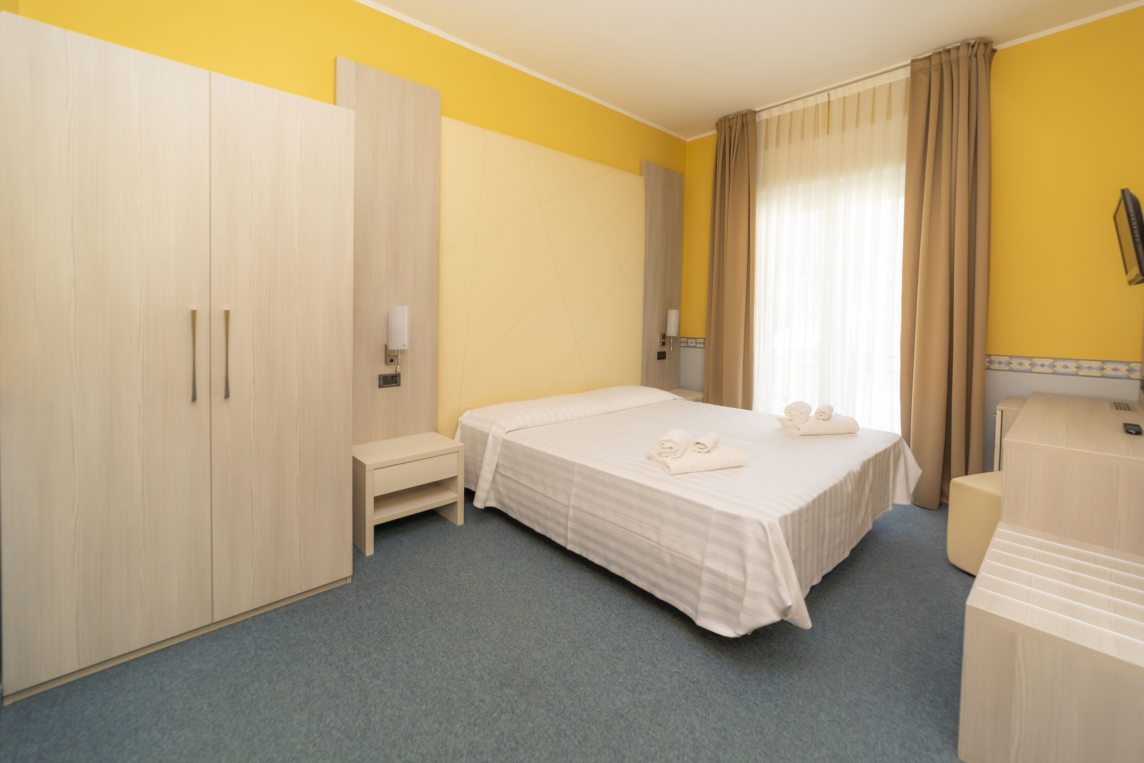 Une chambre d’hôtel comprenant un lit, une armoire, une table de chevet et un bureau.