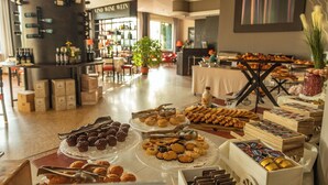A buffet with various pastries and desserts, a wine bar in the background, and a large potted plant in the center. - Hotel Della Torre (Stresa)