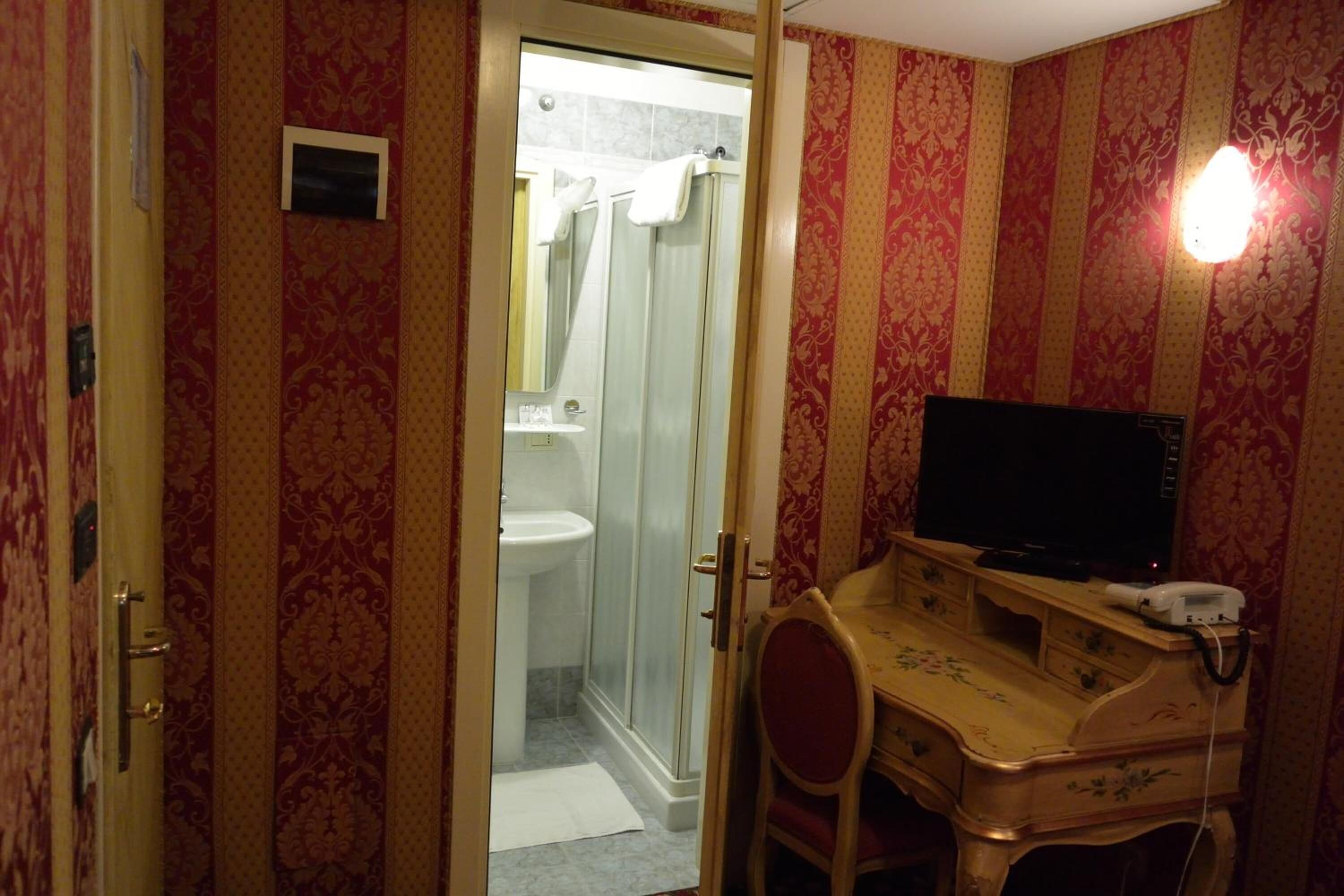 A bathroom with a shower, toilet, and vanity with a television.