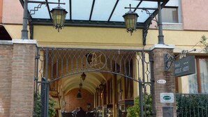 L’entrée d’un hôtel, avec un portail en fer forgé, un tapis rouge et un escalier menant à l’entrée.