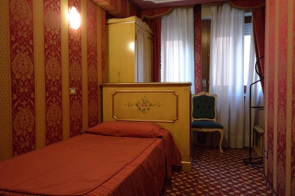 A room with a bed, a wardrobe, a chair, and a desk.