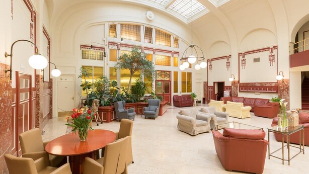 A spacious lobby with a high ceiling, large windows, and a central plant area. - Rho Hotel (Amsterdam)