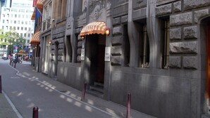 A historic building with a stone facade, a sign for the "Hotel Nescio," and a street view with pedestrians and bicycles. - Rho Hotel (Amsterdam)