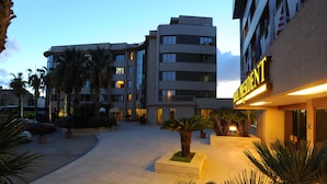 Un patio de hotel con palmeras, piso de baldosas y un edificio con un cartel que dice "HOTEL RESIDENT".
