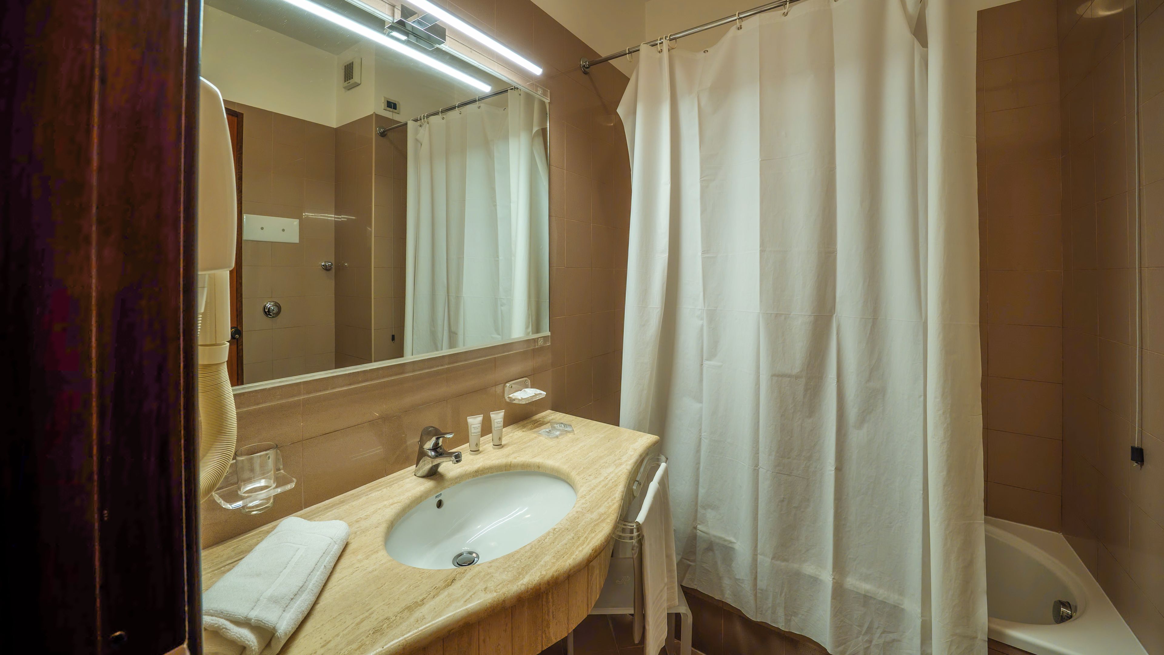 Une salle de bain avec un lavabo, un miroir et un rideau de douche.