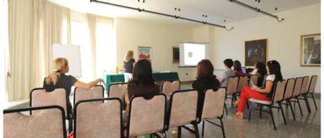 A conference room with a whiteboard, projector, and attendees seated at tables.