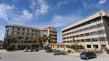 A hotel with multiple floors, a parking lot, and palm trees in the foreground.