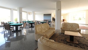Un espacio interior amplio con varias mesas y sillas, un sofá color crema y una mesita.