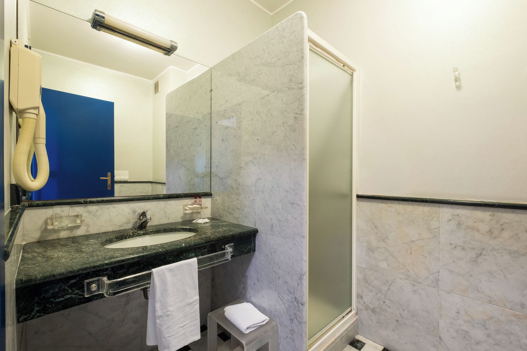 A bathroom with a sink, mirror, and shower.