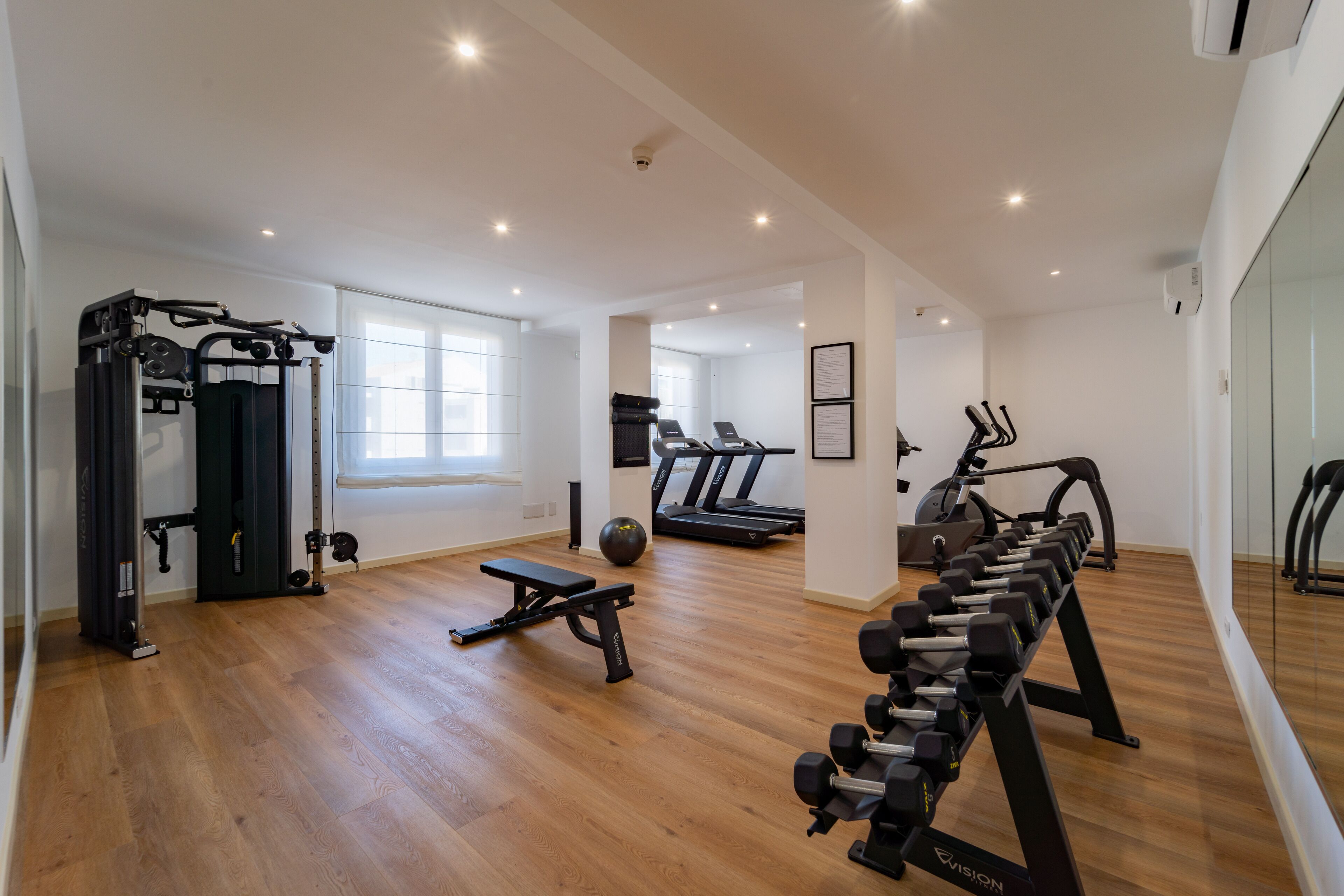 A spacious gym with treadmills, a weight bench, and various exercise equipment.
