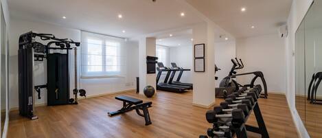A spacious gym with treadmills, a weight bench, and various exercise equipment.