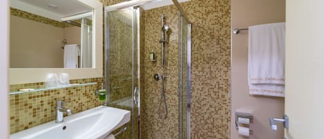 A bathroom with a glass-enclosed shower, a sink with a mirror, and a toilet.