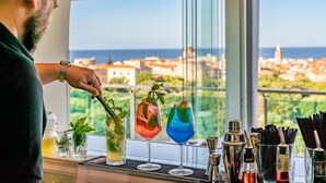 A bartender preparing drinks with a city view in the background. - Hotel Catalunya (Alghero)