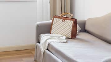 Una stanza con un divano, una lampada e una borsa appoggiata sul divano.