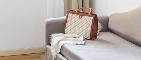 A room with a sofa, a lamp, and a handbag on the sofa.