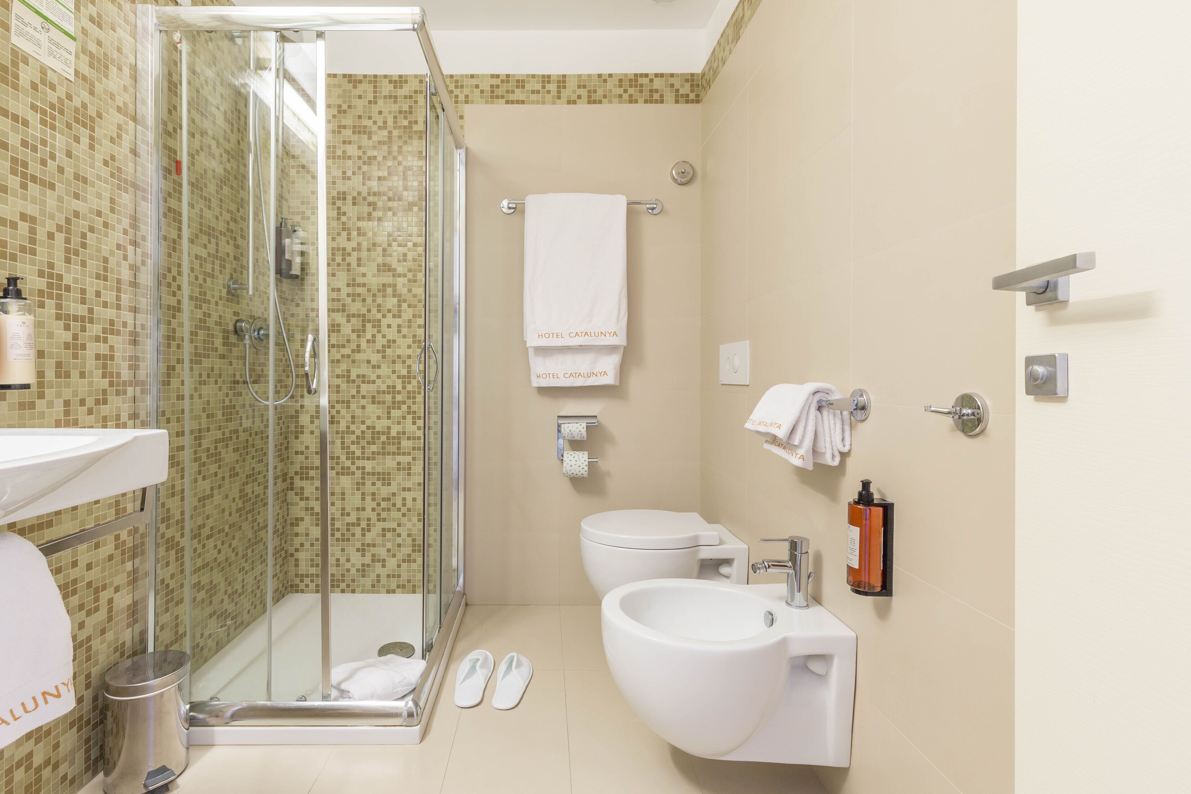 Un baño moderno con ducha envuelta en vidrio, inodoro, bidé y lavamanos.