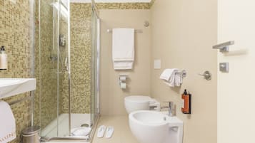 Un baño moderno con ducha envuelta en vidrio, inodoro, bidé y lavamanos.