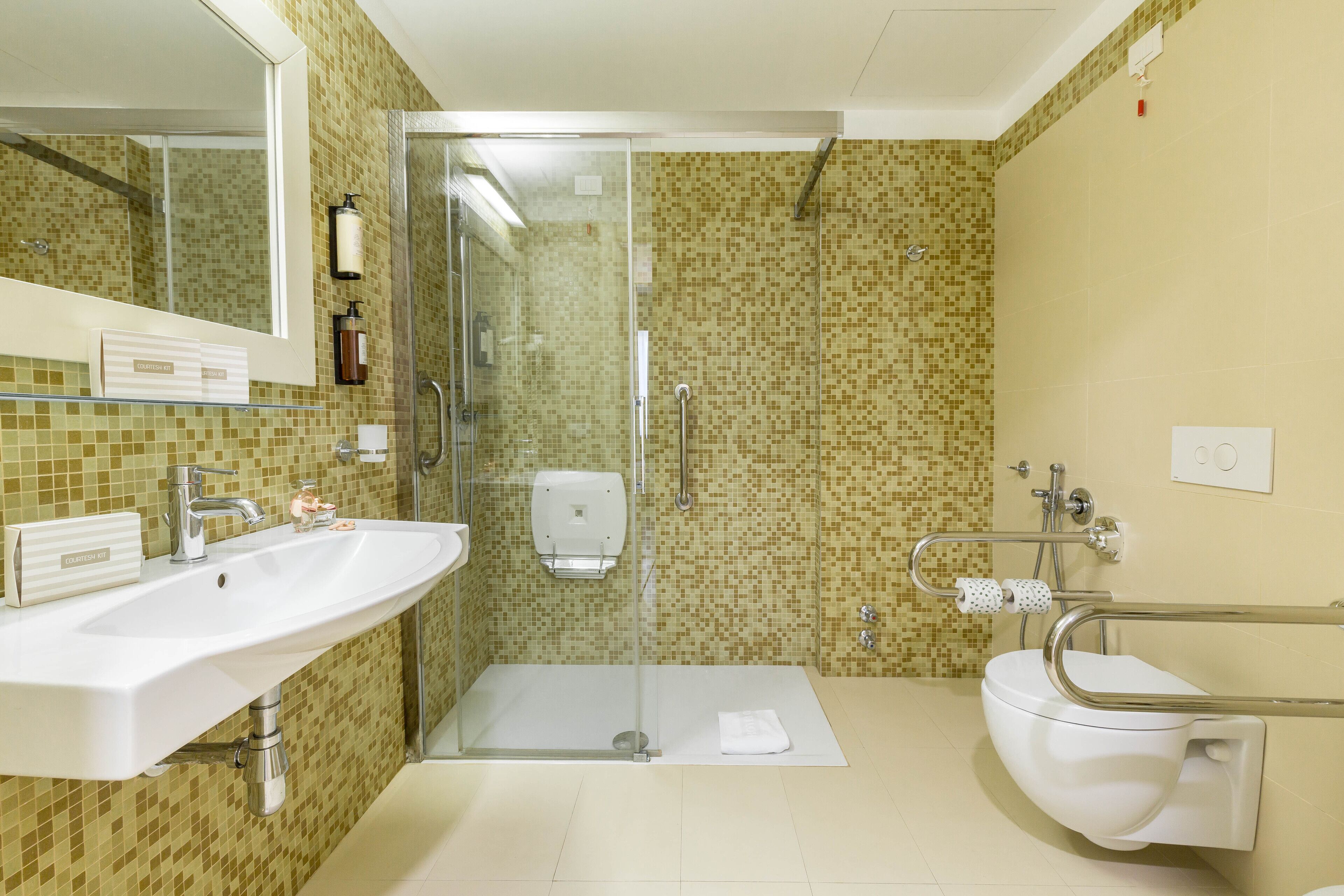 Un baño con ducha de vidrio, lavamanos blanco y retrete.